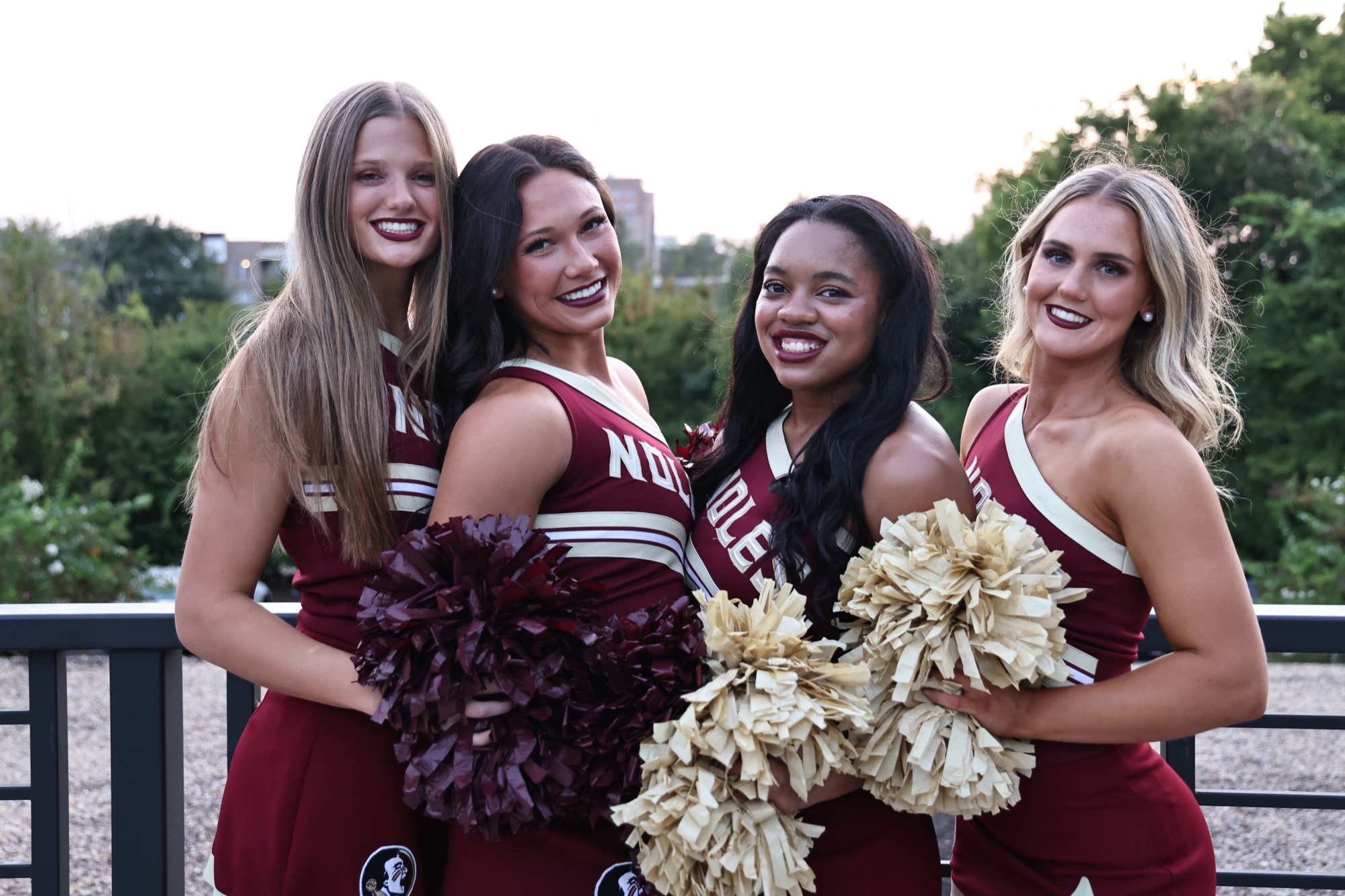 Four Florida State cheerleaders posing together outdoors at dusk
