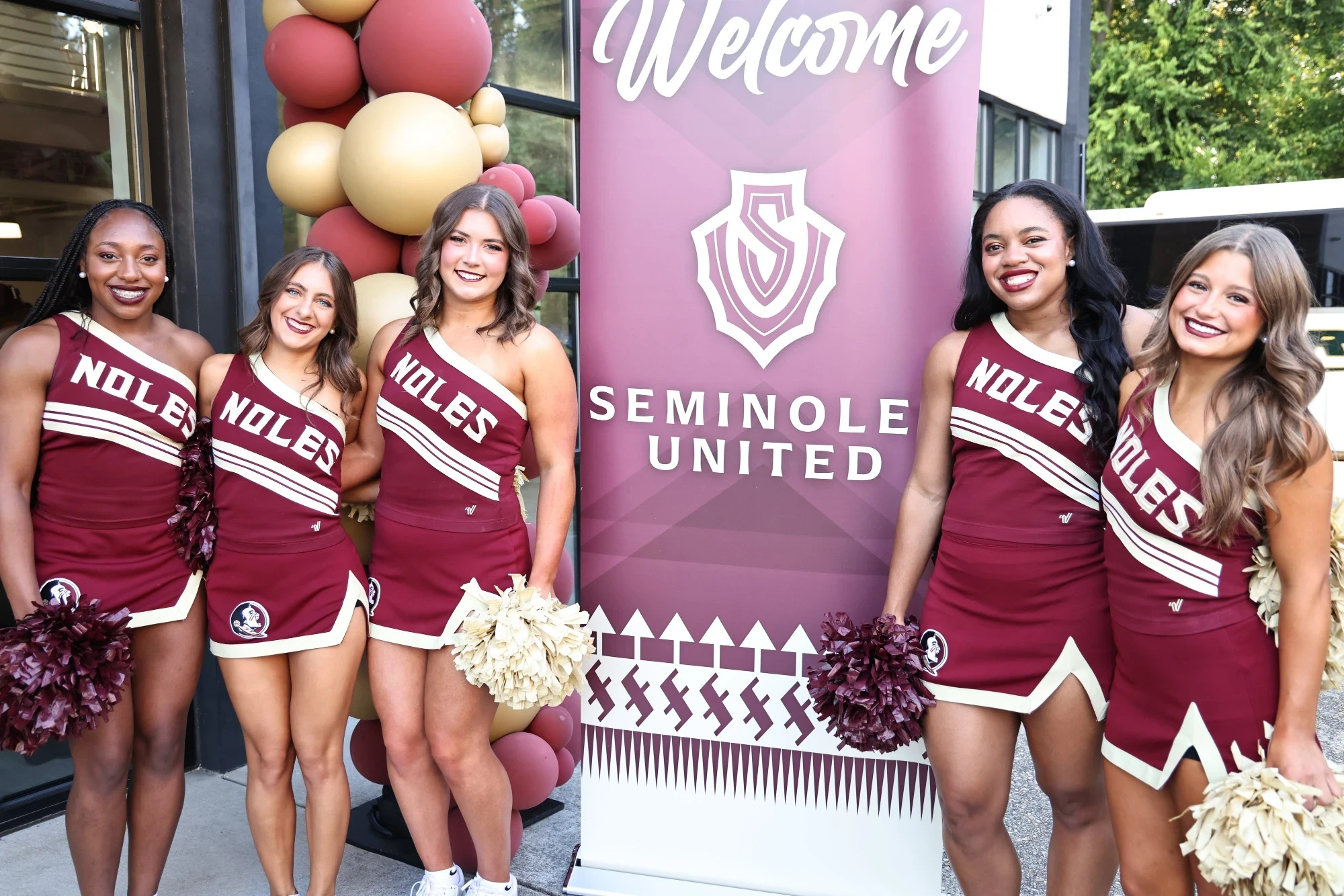 Florida State cheerleaders beside the Seminoles United welcome sign at the FSU vs. Alabama weekend