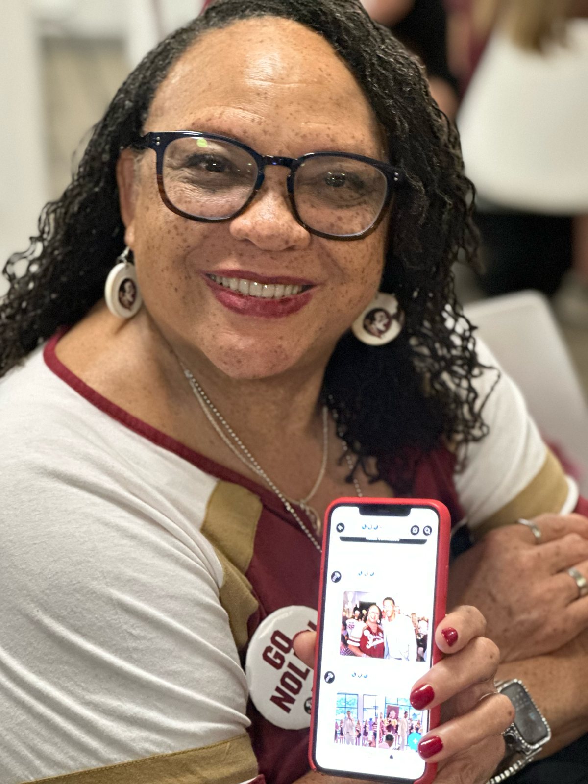 A smiling guest holding up her phone to show her Seminole Snapshot photo gallery
