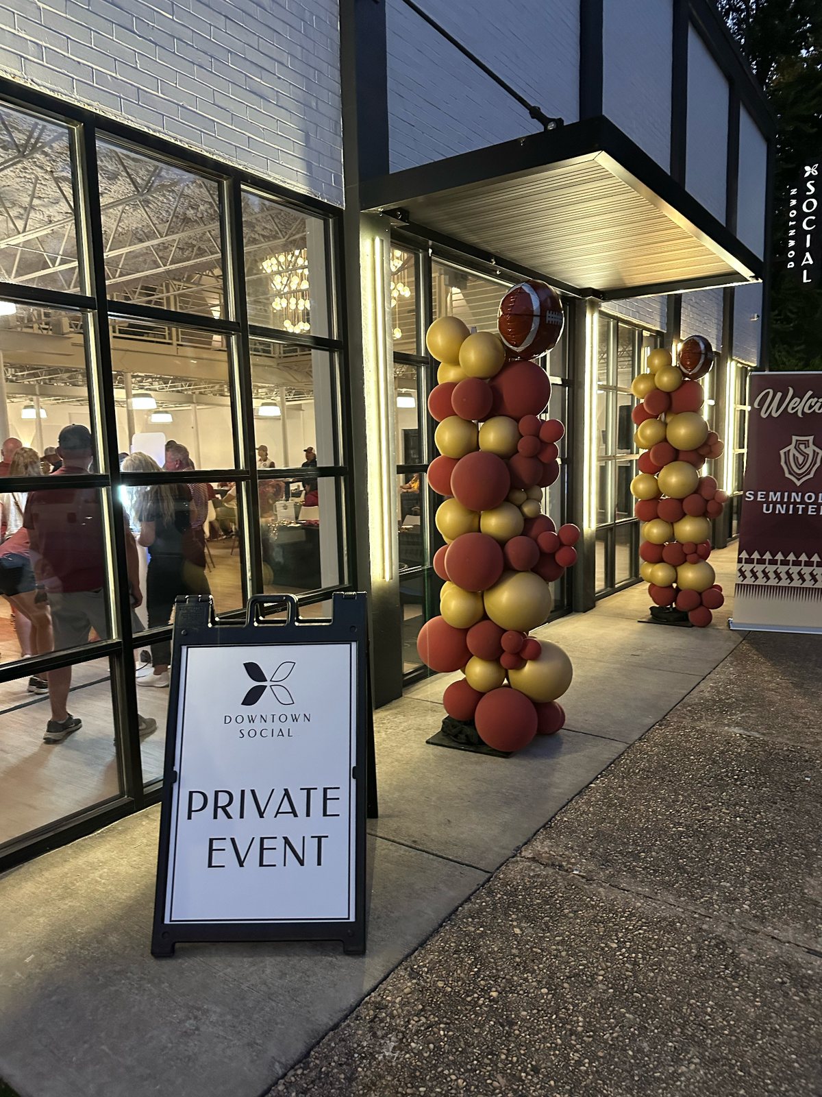 Private event sign and garnet and gold balloons outside Downtown Social