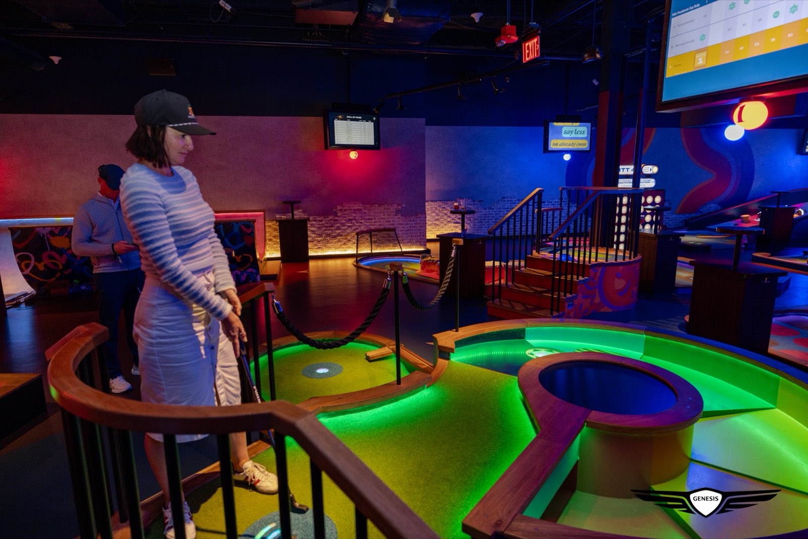A guest playing a brightly lit indoor mini golf course on the Genesis evening out