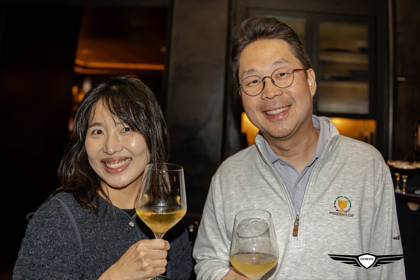 Two Genesis Presidents Cup guests with glasses of wine