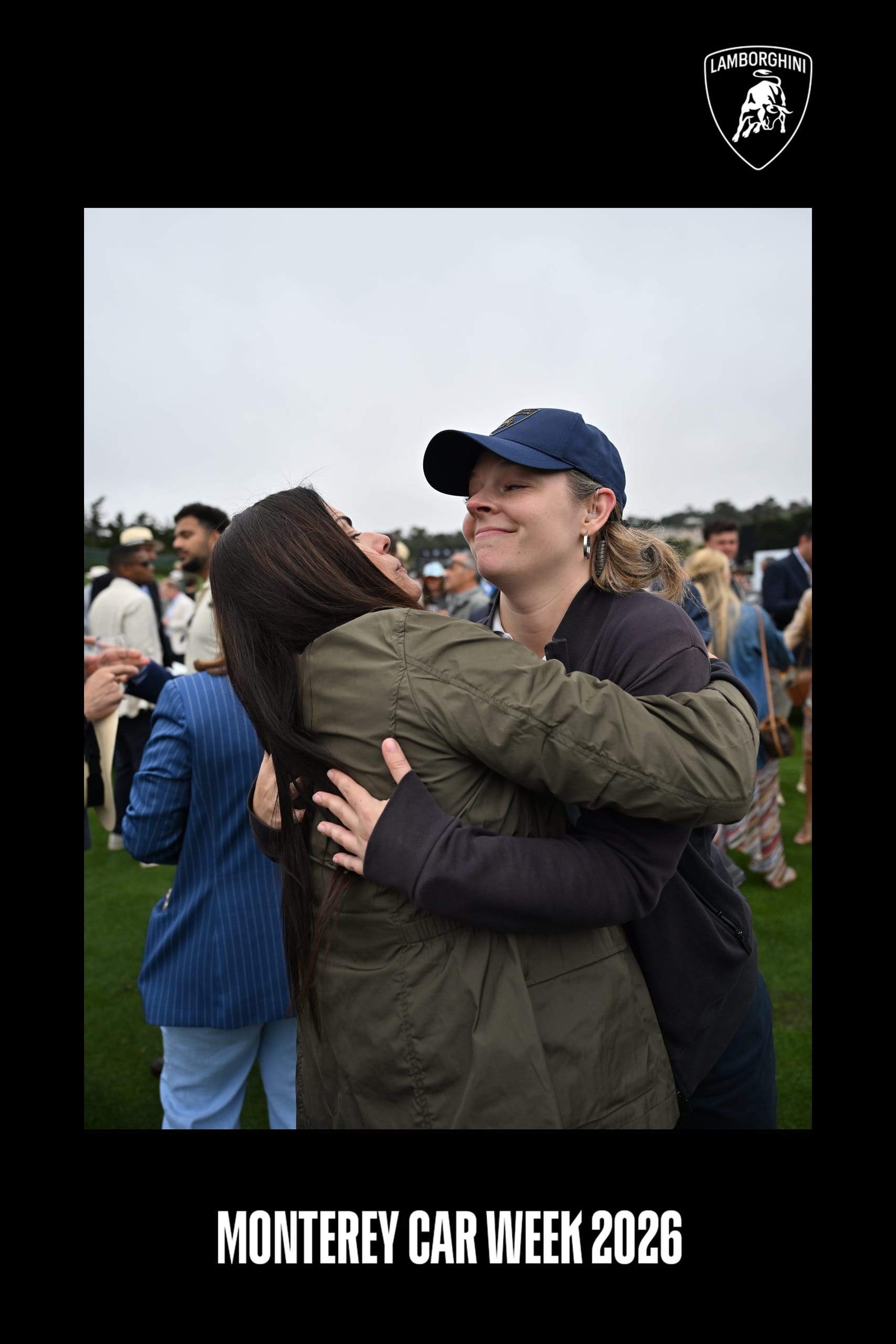 2 guests hugging on the lawn at Monterey Car Week, framed with Lamborghini and Monterey Car Week 2026 branding