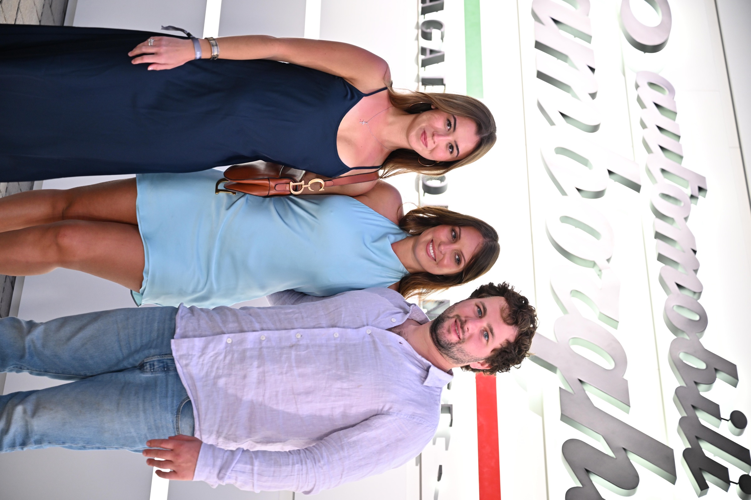 3 guests posing in front of the Automobili Lamborghini sign at Lamborghini Villa