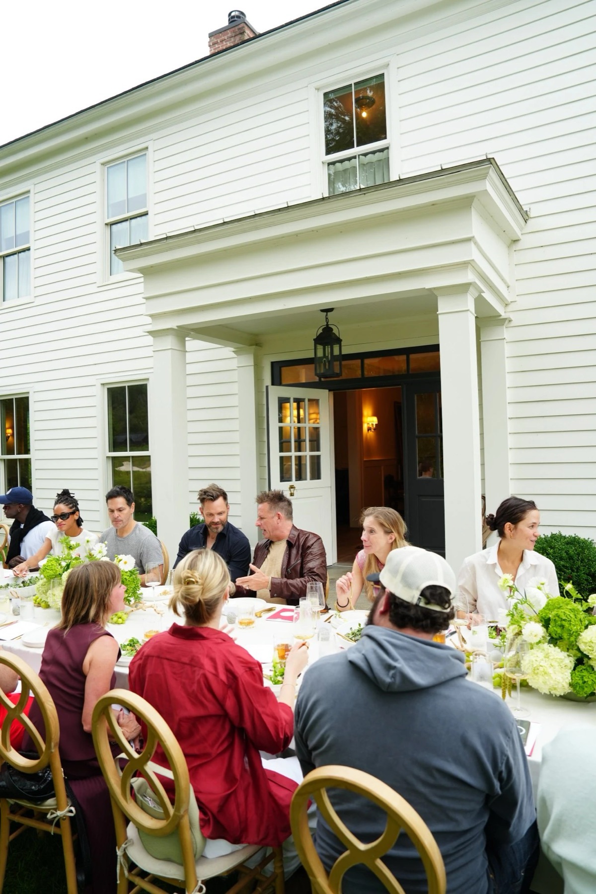 Guests at a long lunch table outside the white INNESS farmhouse