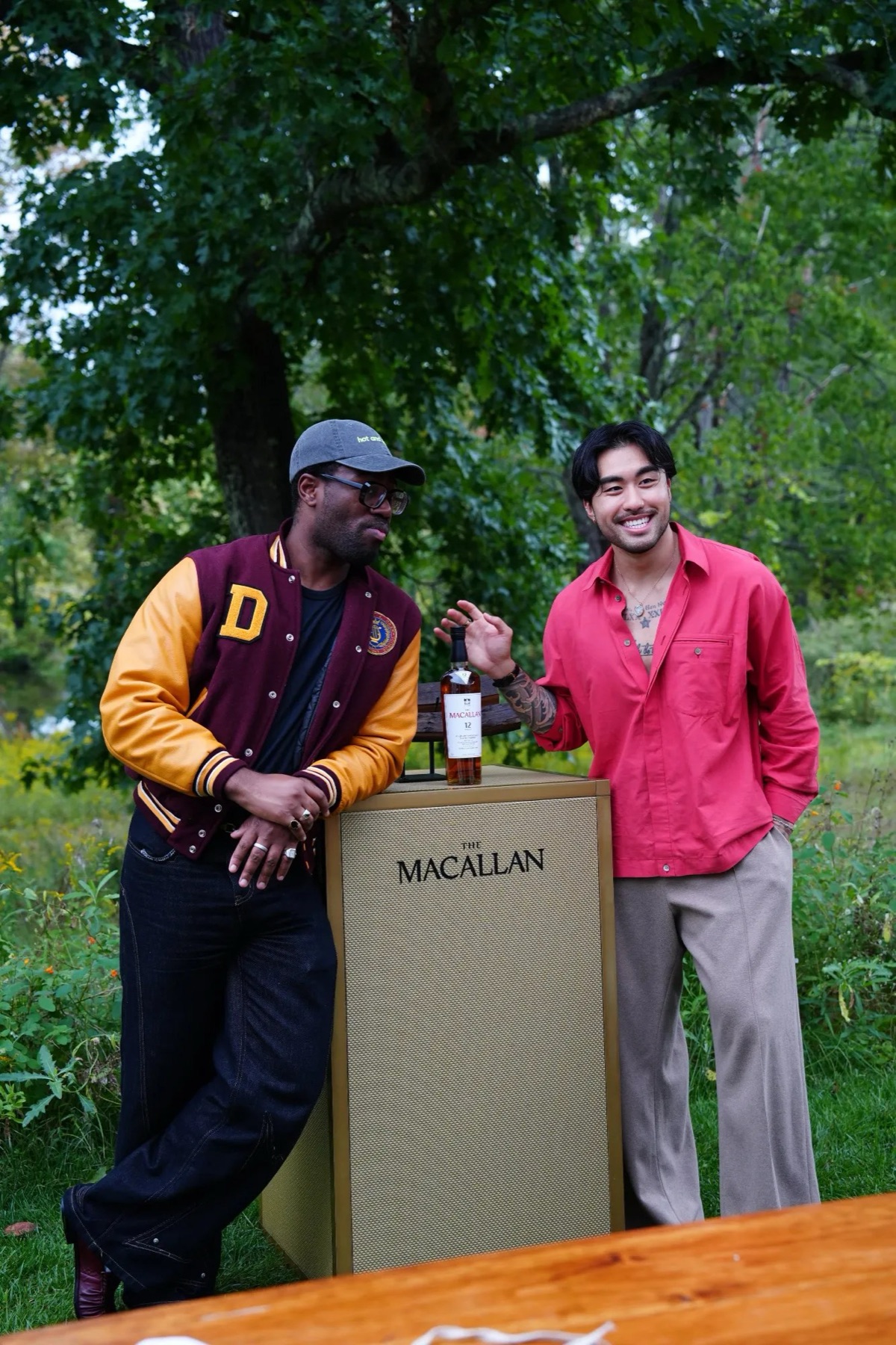 Two guests beside a bottle of The Macallan 12 on the lawn at INNESS
