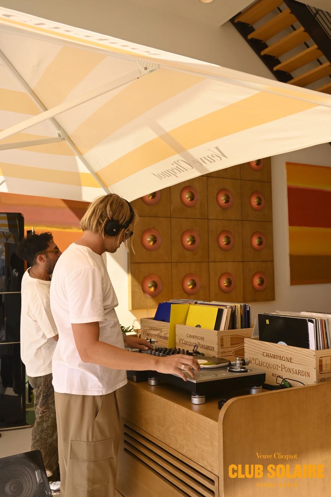 A DJ playing vinyl at Club Solaire beside wooden Veuve Clicquot-Ponsardin record crates
