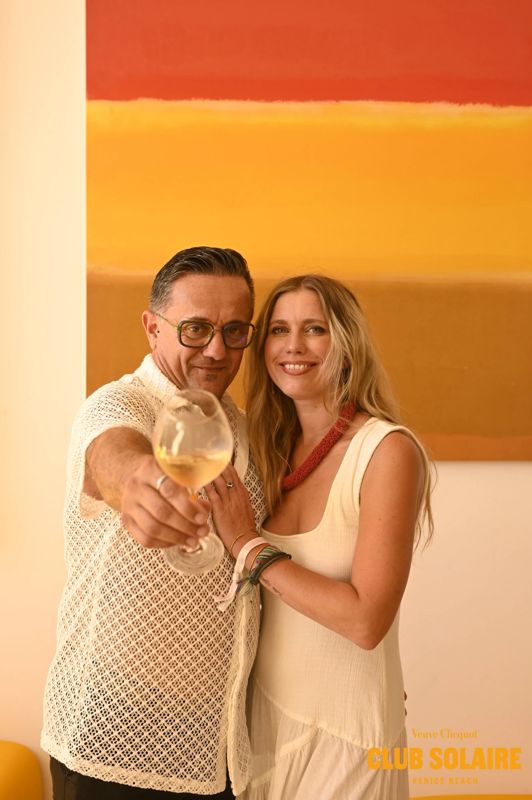 Two Club Solaire guests raising a glass of champagne toward the camera