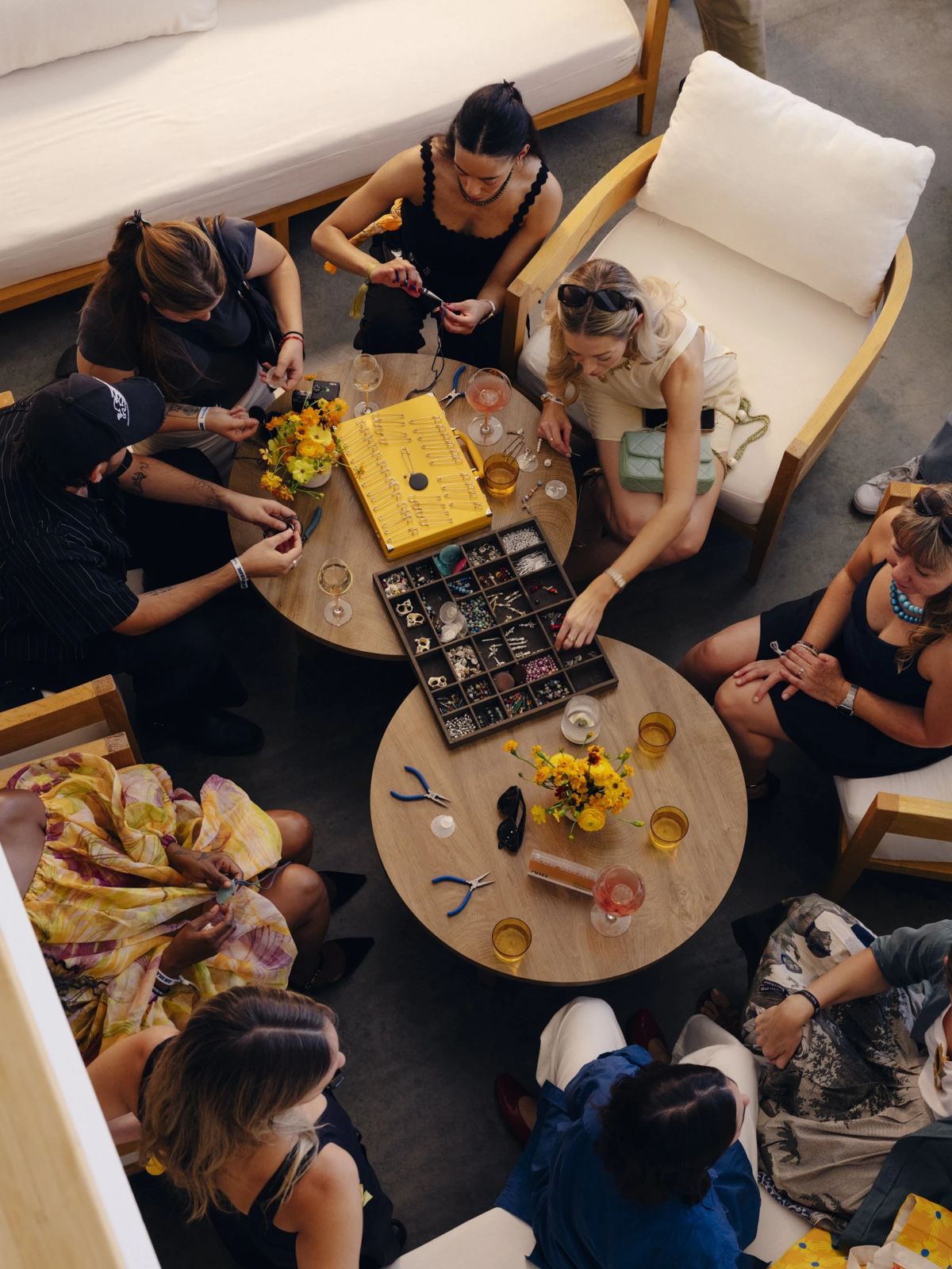 Club Solaire guests seen from above making jewelry around two round tables