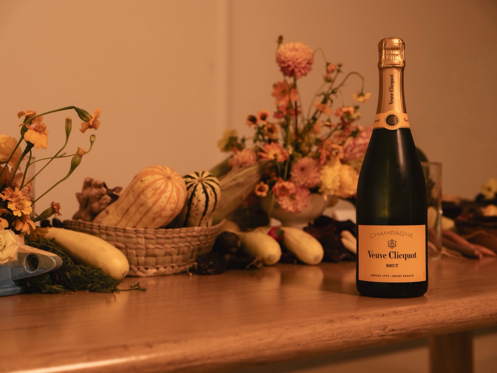 A bottle of Veuve Clicquot Brut on a dinner table with autumn flowers