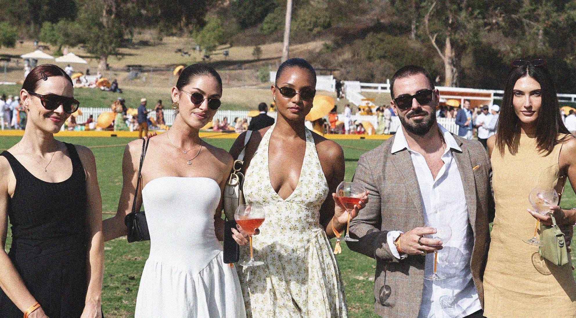 Guests holding champagne on the polo field at the Veuve Clicquot Polo Classic