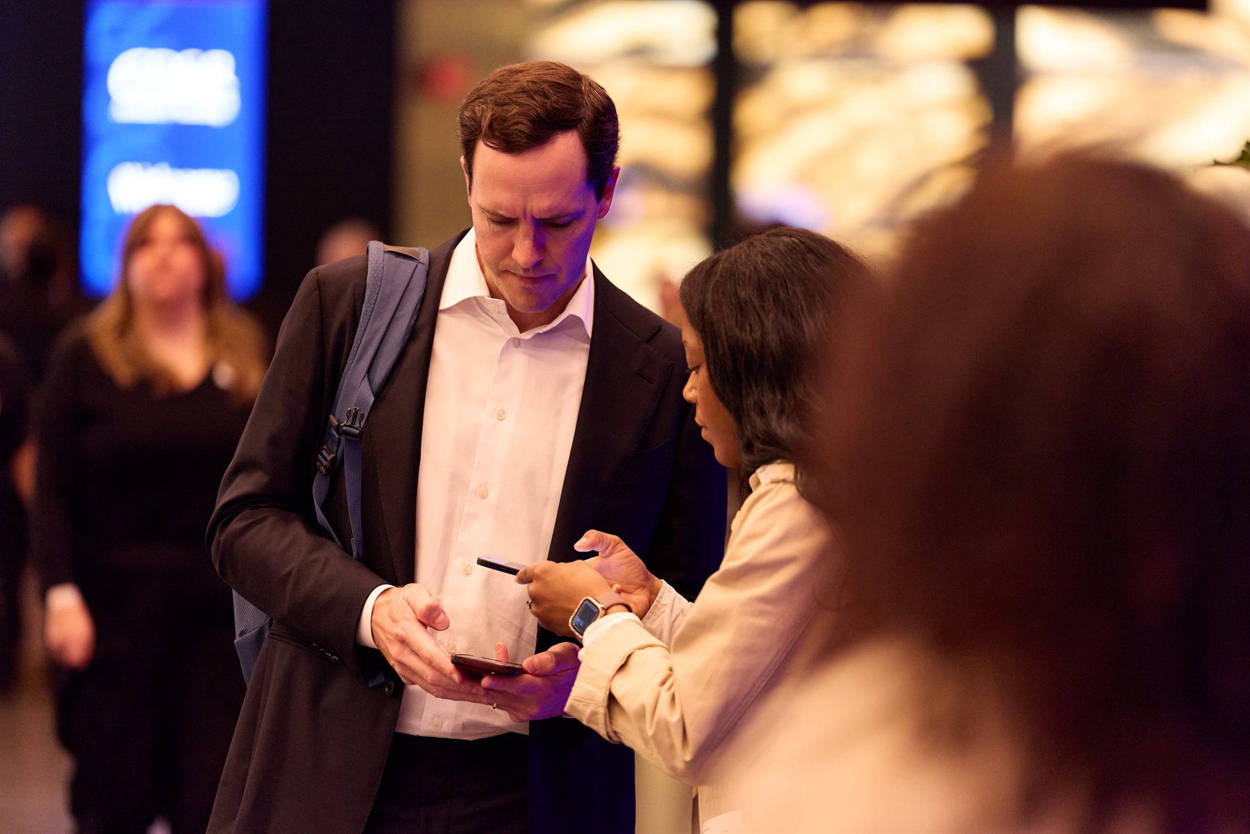 Event staff member helping a guest sign up on his phone at an evening event