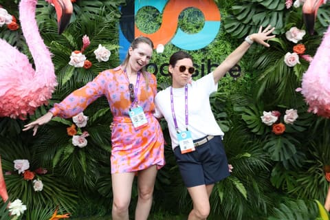 Two attendees posing at a flower wall at Possible